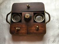Top view of closed wooden box with brass foo dog handles on compartments and two small enameled brass dishes visible inside