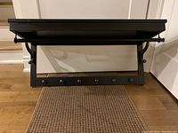 Front view of the black IKEA Hemnes hat rack showing the clothes rail and six metal hooks along the bottom beam.