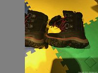 Side profile of the black boots showing outsole tread and buckle straps