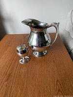 Both silver plated items shown side by side on wooden surface.