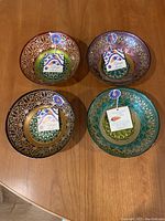 Top view showing all four hand decorated glass bowls with individual Topkapi collection tags. Each bowl features rich colors and intricate gold designs.