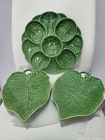 Top view of three glossy green ceramic plates designed as cabbage leaves