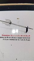 Close-up photo of the rotisserie skewer with three-prong fork showing dimensions printed on the box: 39 L x 3.5 W x 4.75 H inches.