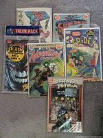 Photo of various Marvel and DC comic books including Spider-Man, Batman, Superman, X-Men, and Weird Adventure Comics.