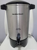 Front view of Hamilton Beach coffee urn showing brand and spigot.