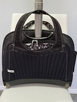 Front view of black rolling laptop bag showing quilted front panel, carry handles and attached telescoping handle.