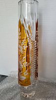 Full side view of a tall clear crystal vase with amber flashing and detailed floral wheel cut engravings.
