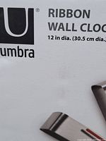 Close-up of Umbra Ribbon Wall Clock branding and size information on box: 12 in diameter (30.5 cm).