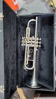 Trumpet inside open black lined hard case showing overall condition and placement.