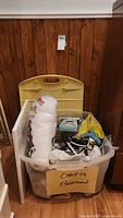 Large plastic bin labeled 'Crafts Bloemen' containing poly-fil, glue tool, pencil crayons, cords and miscellaneous crafting tools.
