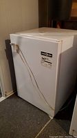 Front angled view of a compact white Kenmore freezer secured with a cord lock, showing the Energy Guide label.