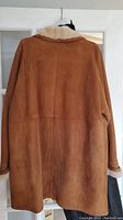 Back view of brown suede shearling coat hanging on door