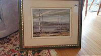 Framed original oil painting showing the full artwork and mat with decorative frame on a patterned carpet.