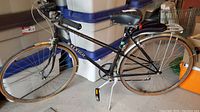 Full left side view of bicycle showing overall frame, wheels, saddle, rack and kickstand