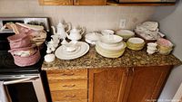 Overview of plates, bowls and serving pieces arranged on kitchen counter, some wrapped in tissue.