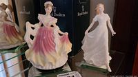 View of 7-inch pink dress music box figurine and 6-inch Friendship figurine in white dress with Royal Doulton boxes behind