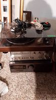 Stacked Hitachi turntable on top of JVC amplifier and tuner with cables laid on dust cover