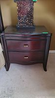 Front view of one night table showing two drawers with curved fronts and metal pulls