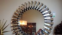 Full front view of round mirror mounted on wall, showing mirrored block frame and interior reflection