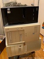 Stacked front view of three desktop towers showing black IBM unit atop two beige units