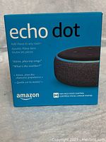 Front view of boxed Amazon Echo Dot with product name, Alexa features, and Amazon branding visible