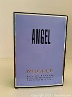 Front view of the closed original box in light purple with 'ANGEL' and 'MUGLER' labeled.