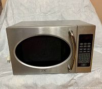 Front view of the RCA microwave showing stainless steel body with oval window and digital control panel on the right side.