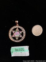 Star of David pendant next to a coin for size reference, showing mother of pearl inlay and 14k rose gold plating over 925 silver.