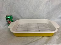 Side view of yellow enamel roasting pan with metal rack inside and 7UP can for size reference.
