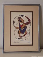 Full view of the framed print artwork showing the figure in hoops within a silver frame and beige matting.