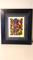 Framed limited edition Norval Morrisseau print in black frame with white matting and vibrant colors.