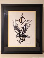 Framed Indigenous artwork featuring a bird under an abstract circular symbol with black and tan accents.