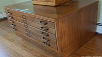 Overall view of oak flat file cabinet on hardwood floor with smaller box on top
