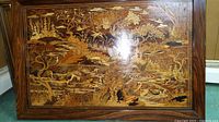Full image showing carved wooden panel with detailed nature scene including birds, plants, water, and trees in a wood frame.