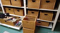 Shelving unit filled with multiple wicker baskets and one pulled out drawer