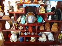 Full shelf display of assorted stone Buddha figurines