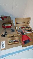Overview photo showing multiple woodworking tools including carving knives, blades, dustpan and brush, and bench vise.