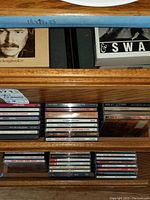 Photo of three drawers filled with various music CDs in jewel cases, some boxed sets, and a songbook visible on the top drawer.