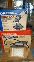 Box of Dremel Moto-Tool Holder & Base Model 2217 on top of box of Dremel Moto-Flex Tool Model 232 along with a small cardboard box.