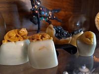 Front view: two pale green seals with mustard yellow beast toppers and three yellow seals with black carvings in front of horse figurine and plate