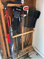 Photo showing golf clubs standing vertically in wooden rack with head covers including Tour Edge and Bazooka