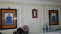 Three framed Japanese tile wall plaques displayed side by side above a shelf