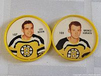 Two circular Sheriff coins featuring Boston Bruins players Leo Boivin and Bronco Horvath in yellow bordered coins with player info and Bruins jerseys visible.