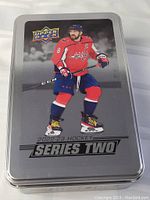 Metal tin container with image of hockey player in red Washington Capitals uniform and '2022-23 Hockey Series Two' branding.
