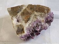 Amethyst cluster showing purple pointed crystals and matrix rock with white quartz areas from top angle.