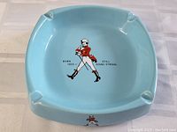 Top down view of the light blue ashtray showing the central Johnny Walker logo with text 'BORN 1820 - STILL GOING STRONG'