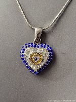 Close-up of the heart-shaped pendant showing blue, white, and yellow stones on sterling silver.