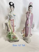 Front view of the two porcelain Asian woman figurines with floral designs standing side by side, about 12 inches tall each.