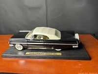 Black and white 1959 Chevrolet Impala scale model car mounted on wooden base showing side profile with white hardtop roof and chrome details.