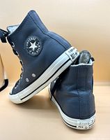 Side view of black leather Converse All Star shoes showing logo patch and heel label